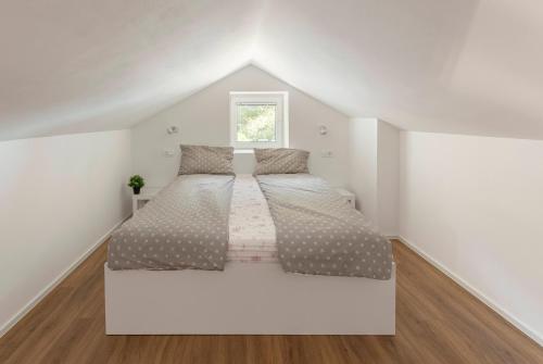 a white bedroom with two beds in a attic at Apartments Berni in Ljubljana