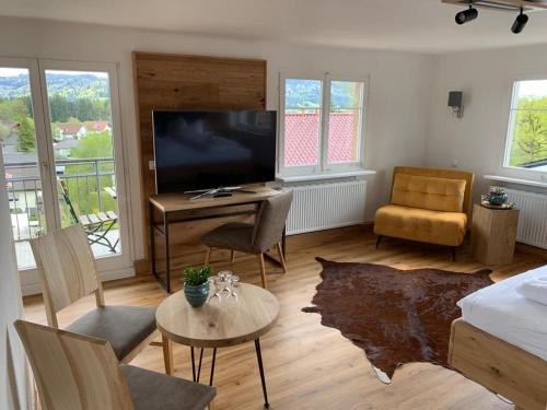 sala de estar con TV, mesa y sofá en Landhaus Sonne, en Hergensweiler