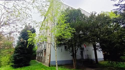 biały budynek z drzewami przed nim w obiekcie DROINVEST Apartament Jarzębinowa - Wrocław KRZYKI - PKP - UE we Wrocławiu