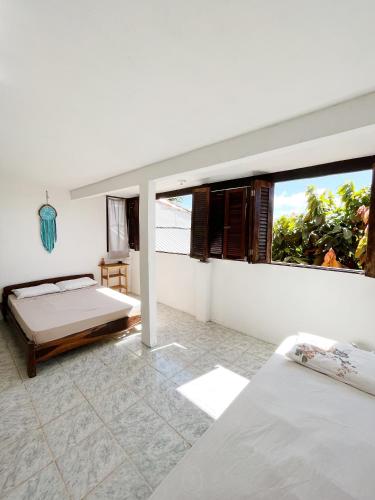 a bedroom with two beds and a large window at Morada Cacauêra in Itacaré