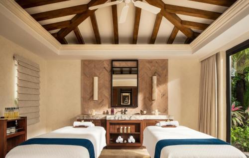 two beds in a room with a sink and a mirror at One&Only Palmilla in San José del Cabo