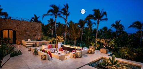 a patio with couches and a pool and palm trees at One&Only Palmilla in San José del Cabo