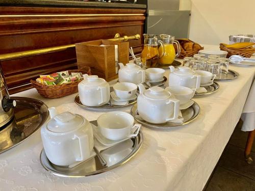 una mesa con tazas blancas y platillos en ella en Hotel Majovey en Žilina