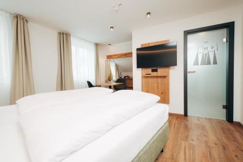 a hotel room with a large white bed and a television at Hotel Drei König in Immenstadt im Allgäu