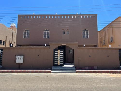 un grand bâtiment marron avec une porte et des escaliers. dans l'établissement السلطان للشقق المفروشة, à Al-Ula