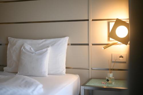 a bed with a white pillow and a lamp on a table at Villa Nicolli Romantic Spa Resort - Adults Only in Riva del Garda
