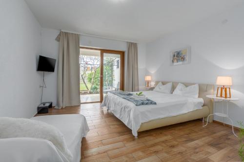 a white bedroom with a bed and a window at Apartments Zomzi in Poreč