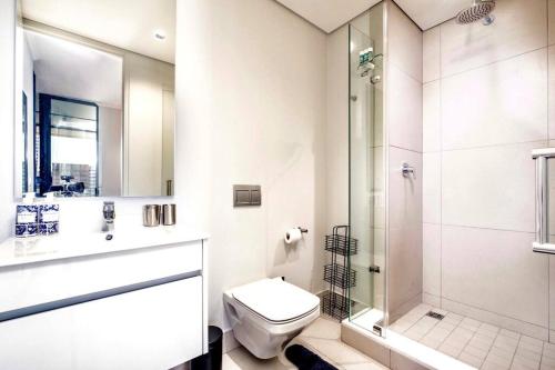 a white bathroom with a shower and a toilet at Keza Cove at Waterfall Ellipse in Midrand
