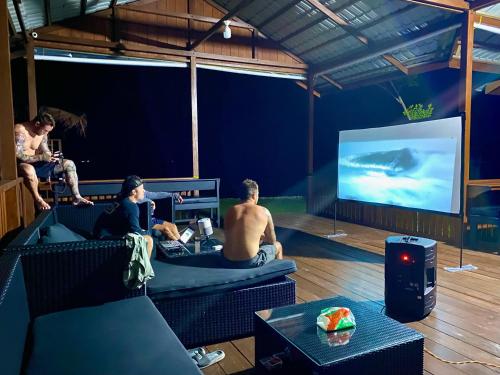 a group of people sitting on couches watching a tv at Surge Surf Villas in Lasikin