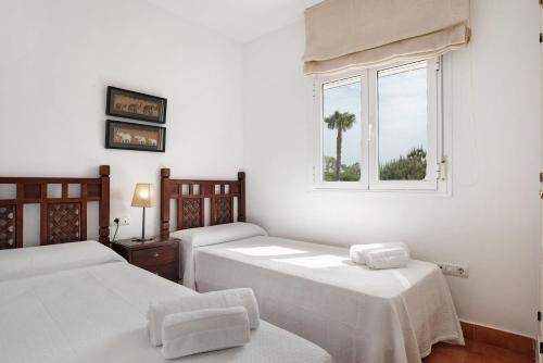 a white room with two beds and a window at Apartamento Sancti Petri in Chiclana de la Frontera