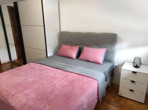 een slaapkamer met een bed met 2 roze kussens bij Apartman Dionis Centar in Trebinje