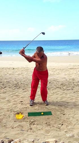 a man swinging a bat at a ball on the beach at Casa Djarmai Boutique Apartments in Vila do Maio