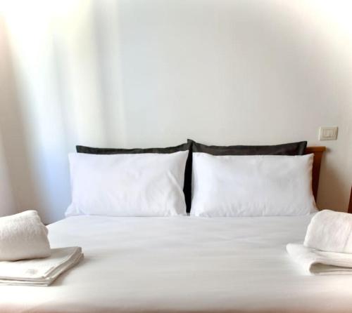 un letto con cuscini bianchi e 2 asciugamani di Civico 18- La tua casa in centro a Latina
