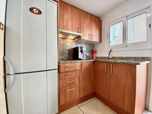 - une cuisine avec des placards en bois et un réfrigérateur blanc dans l'établissement Punta rocosa, à Platja d'Aro