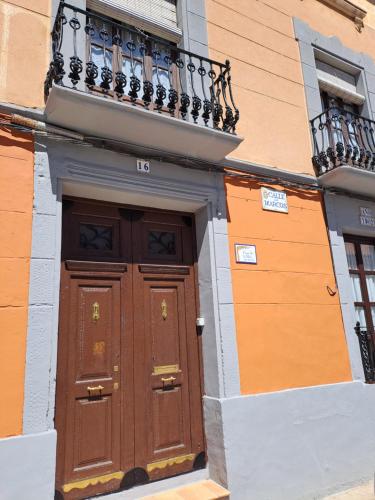 a building with a wooden door and a balcony at Casa de La Parra in Valverde de Júcar