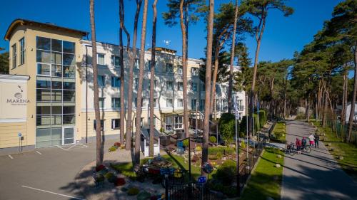 a building with palm trees in front of a street at Marena Wellness & Spa in Międzywodzie