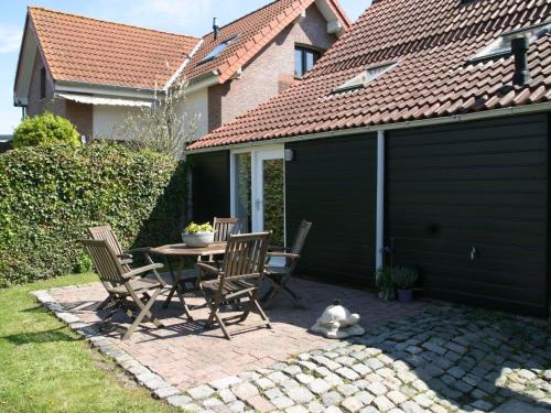 a patio with a table and chairs next to a garage at Holiday Home Helmrich by Interhome in Schoondijke