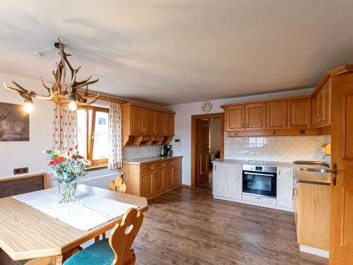 a kitchen with wooden cabinets and a table with flowers on it at Holiday Home Haus Weickl by Interhome in Kaprun