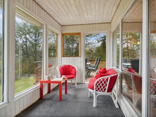 un porche cubierto con sillas rojas y una mesa en Holiday Home Hristijan - 300m to the inlet in The Liim Fiord by Interhome, en Løgstør