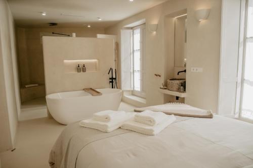 een witte badkamer met een bad en een bed bij EntreArcos Casa Eco-Boutique in Vejer de la Frontera