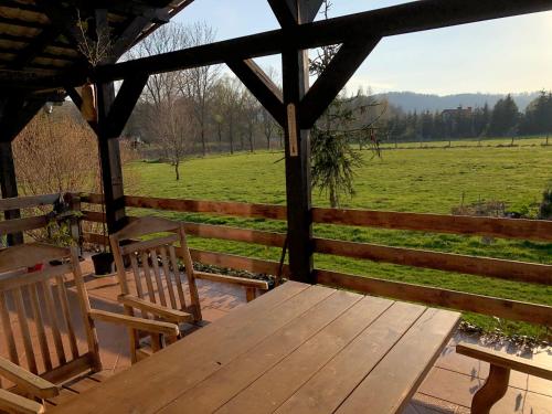 a wooden table and chairs on a porch with a view of a field at zielonapogoda in Lądek-Zdrój
