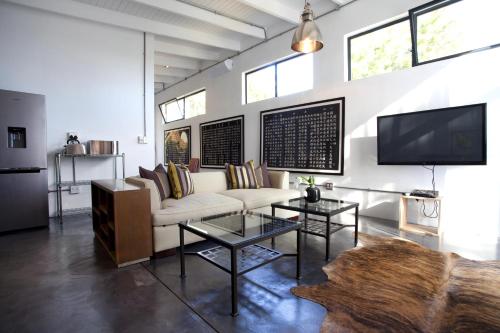 a living room with a white couch and a tv at Sugarbird Manor in Stellenbosch