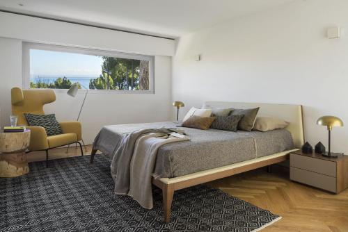 a bedroom with a bed and a chair and a window at BelleVue in Cala Vinyes