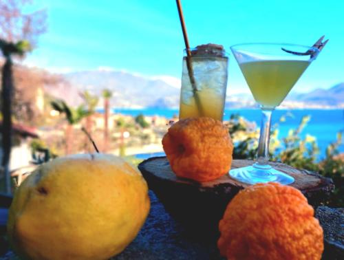 two oranges and a drink on a table with a view at Hotel La Rondinella in Cannero Riviera