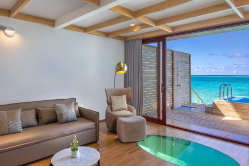 a living room with a couch and a view of the ocean at NOOE Maldives Kunaavashi in Fulidhoo