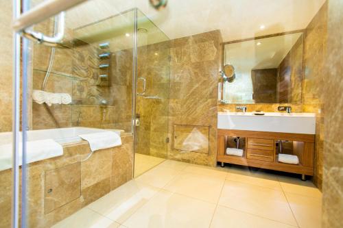y baño con ducha, lavabo y bañera. en Abuja Continental Hotel en Abuja
