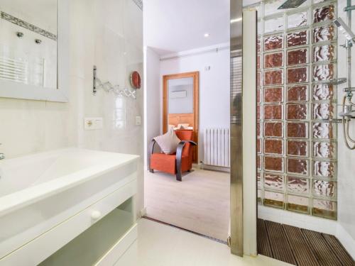 ein Badezimmer mit einer Badewanne und einer Glastür mit einem Stuhl in der Unterkunft Villa Nacho in Port de Pollença