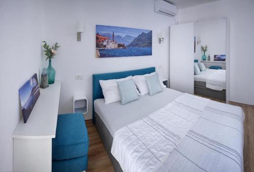 biała sypialnia z łóżkiem i niebieskim krzesłem w obiekcie Solimar w Budvie