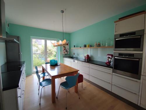 - une cuisine avec une table en bois et des murs bleus dans l'établissement Zen Apartment - spacious - garden - kitchen, à Karlsruhe