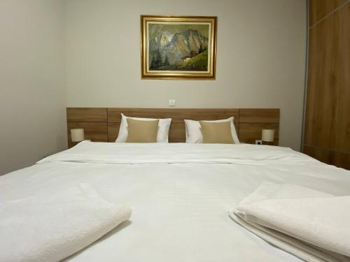 een groot wit bed met witte lakens en kussens bij Miris tisine in Zlatibor