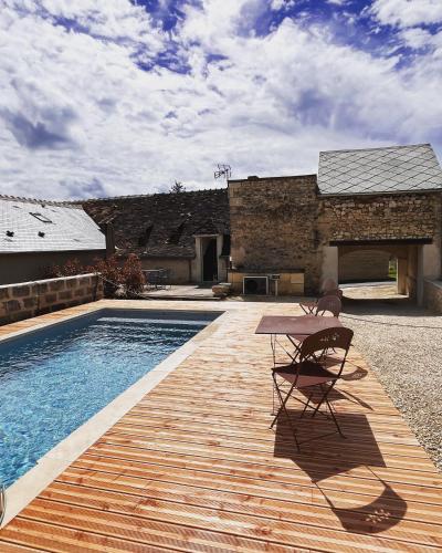 une table et une chaise assises sur une terrasse à côté d'une piscine dans l'établissement Maisons d'hôtes du Château au Grand Pressigny, à Le Grand-Pressigny