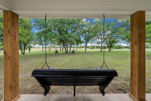 a porch swing with a view of a park at 50 Acre Countryside Haven With Hiking Trails, Fossils, Pickleball Court, Basketball, Arcade, In-Ground Trampoline, Pool and Jacuzzi residence in Glen Rose