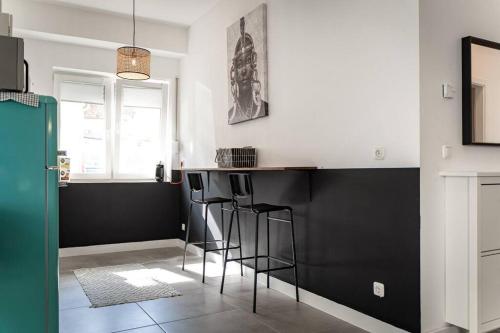 a kitchen with black and white walls and bar stools at Moderne Wohnung im Herzen Offenbachs in Offenbach