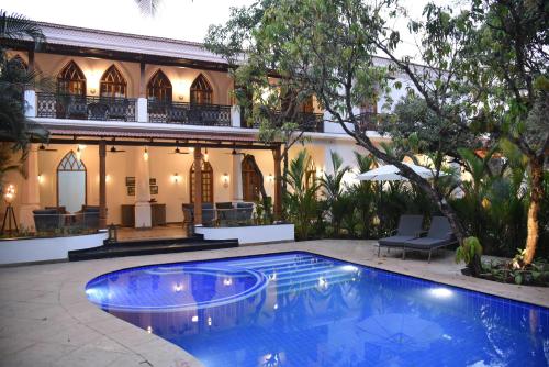 a swimming pool in front of a house at The Postcard Saligao in Calangute