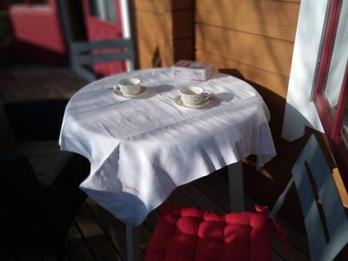 a white table with two cups and saucers on it at Chalet au calme cœur du LOT in Mauroux