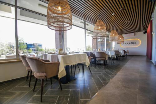 - un restaurant avec des tables, des chaises et de grandes fenêtres dans l'établissement Ardager Residence, à Atyraū