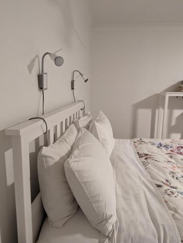 a white bed with two pillows and two lamps at Twodogfolly at Creeklands in Armidale