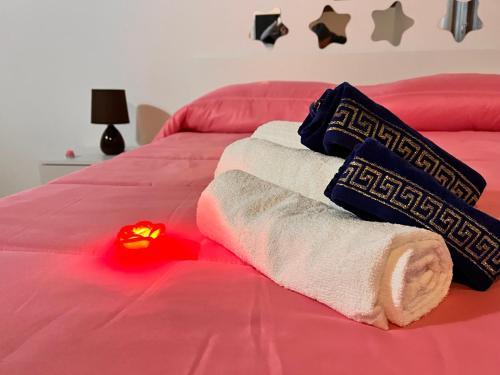 Una cama roja con toallas y una luz roja. en Upupa B&B Casa Vacanza, en Sessa Cilento