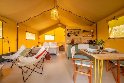 Cette chambre dispose de murs jaunes, d'une table et de chaises. dans l'établissement The Firs Luxury Lodges and Glamping Tents, à Cratfield