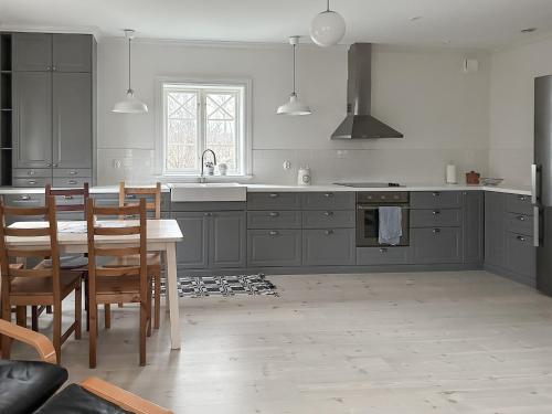 a kitchen with gray cabinets and a table and chairs at Vallby Cottage in Enköping