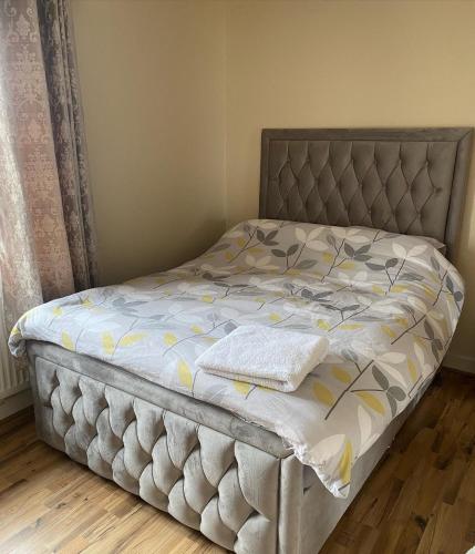 uma cama num quarto com uma cabeceira cinzenta em Bonnyglen kitchen Bar & Guest House em Frosses