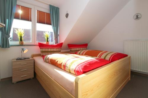 a bedroom with a wooden bed with red pillows at Ferienwohnungen Wiese in Norddeich