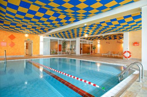 a large swimming pool with a blue and yellow ceiling at Alpenjuwel in Scheidegg