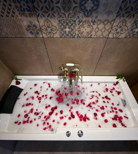 a bathroom sink filled with red petals on it at BBC Luxury Apartments in Perintalmanna