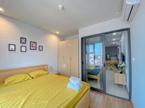 a bedroom with a yellow bed and a sliding glass door at Rio Ha Long Homestay - Green Bay Garden A1605 in Ha Long