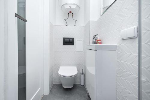 ein weißes Bad mit einem WC und einem Waschbecken in der Unterkunft Apartament Zwycięstwa in Gliwice